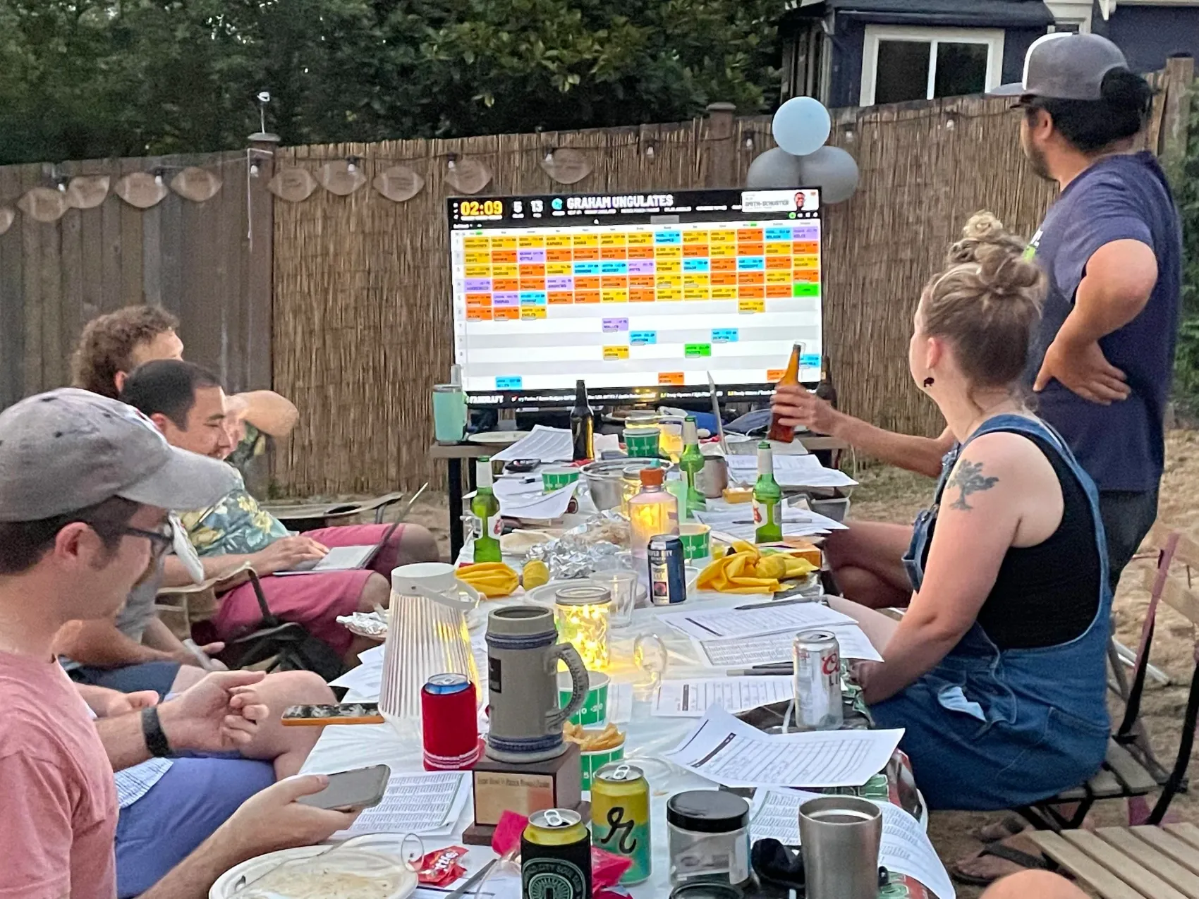 A FanDraft fantasy football draft party gathered in a backyard around the draft board